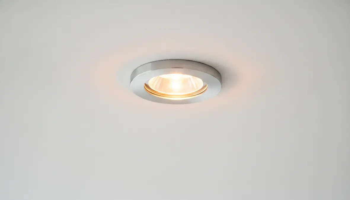 Dettaglio faretto LED da incasso circolare con luce calda installato in controsoffitto bianco